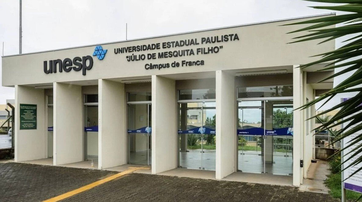 Estudantes comemorando a aprovação no Vestibular UNESP 2025 em frente ao campus universitário.